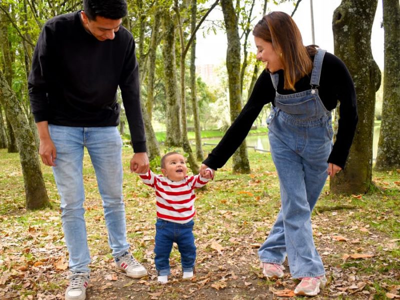 A joyful family enjoys a walk under lush green trees in the park.