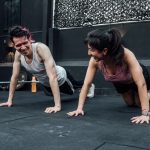 Man and woman doing pushups while smiling during a workout inside a Mexico City gym.