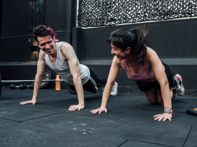 Man and woman doing pushups while smiling during a workout inside a Mexico City gym.